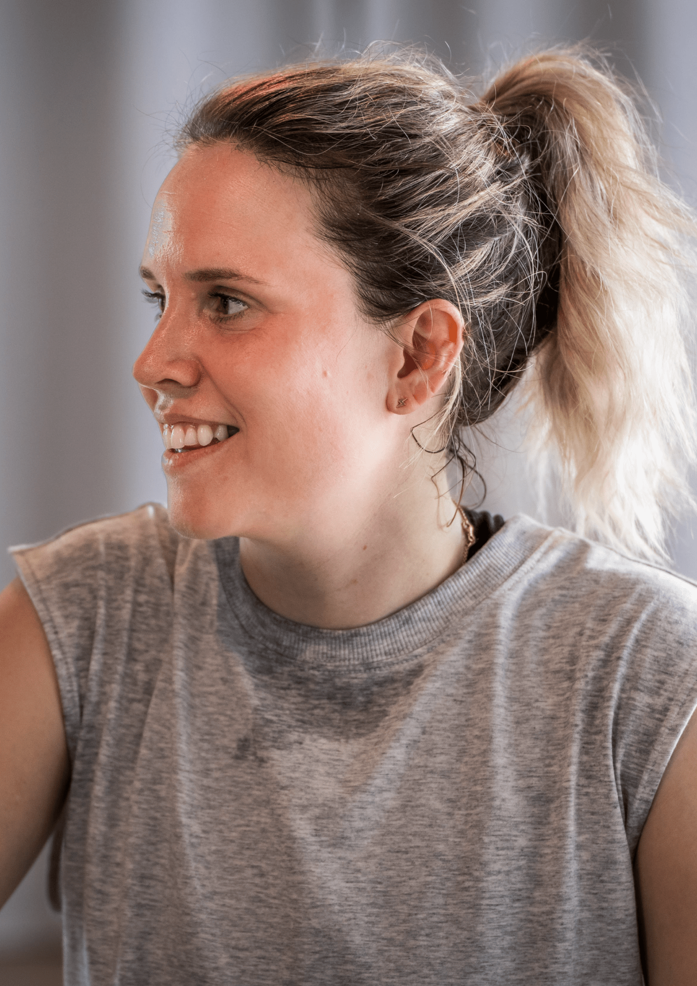 Eine lächelnde Frau in grauem Shirt, sportlich aktiv, von Goldenbody Shop Ch inspiriert.