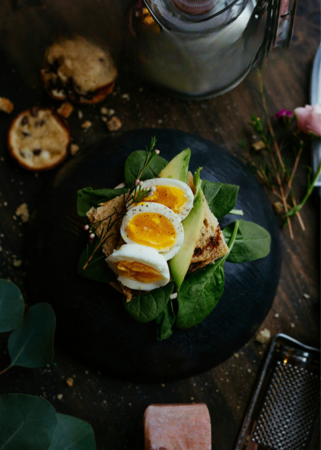 Ein belegtes Brot mit Avocado und Ei auf dunklem Teller, Goldenbody Shop Ch.