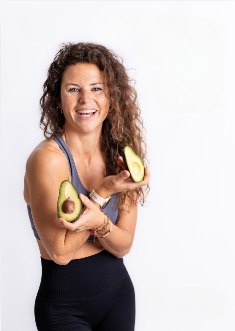Eine lächelnde Frau hält zwei Avocadohälften, präsentiert von Goldenbody Shop Ch.