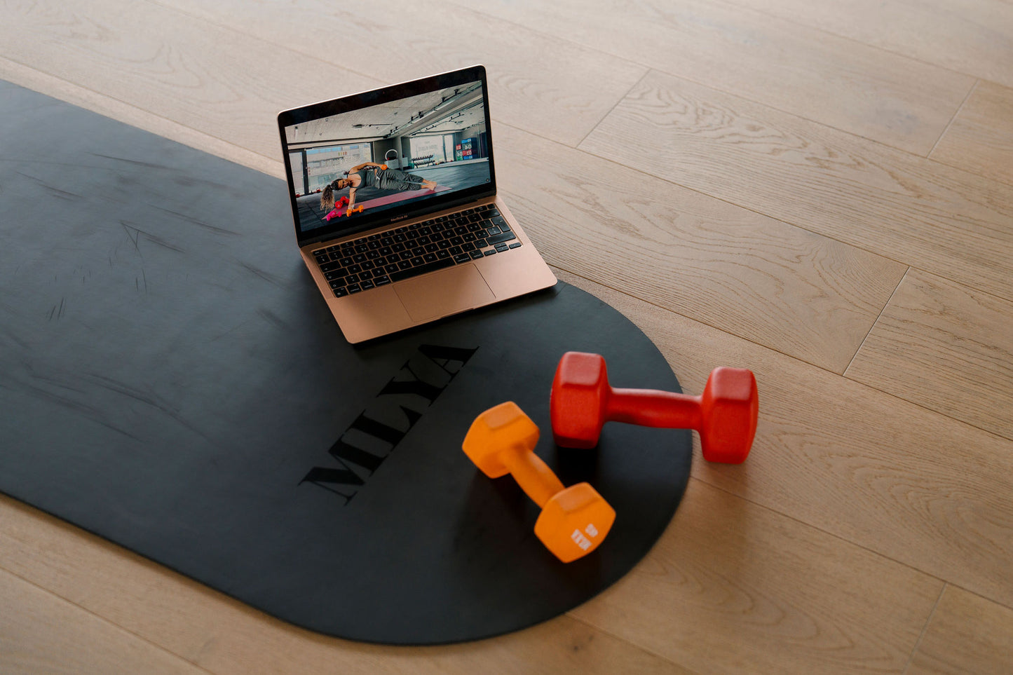 Laptop zeigt Online-Workout auf Matte mit Hanteln, ideal für Goldenbody Shop Ch.