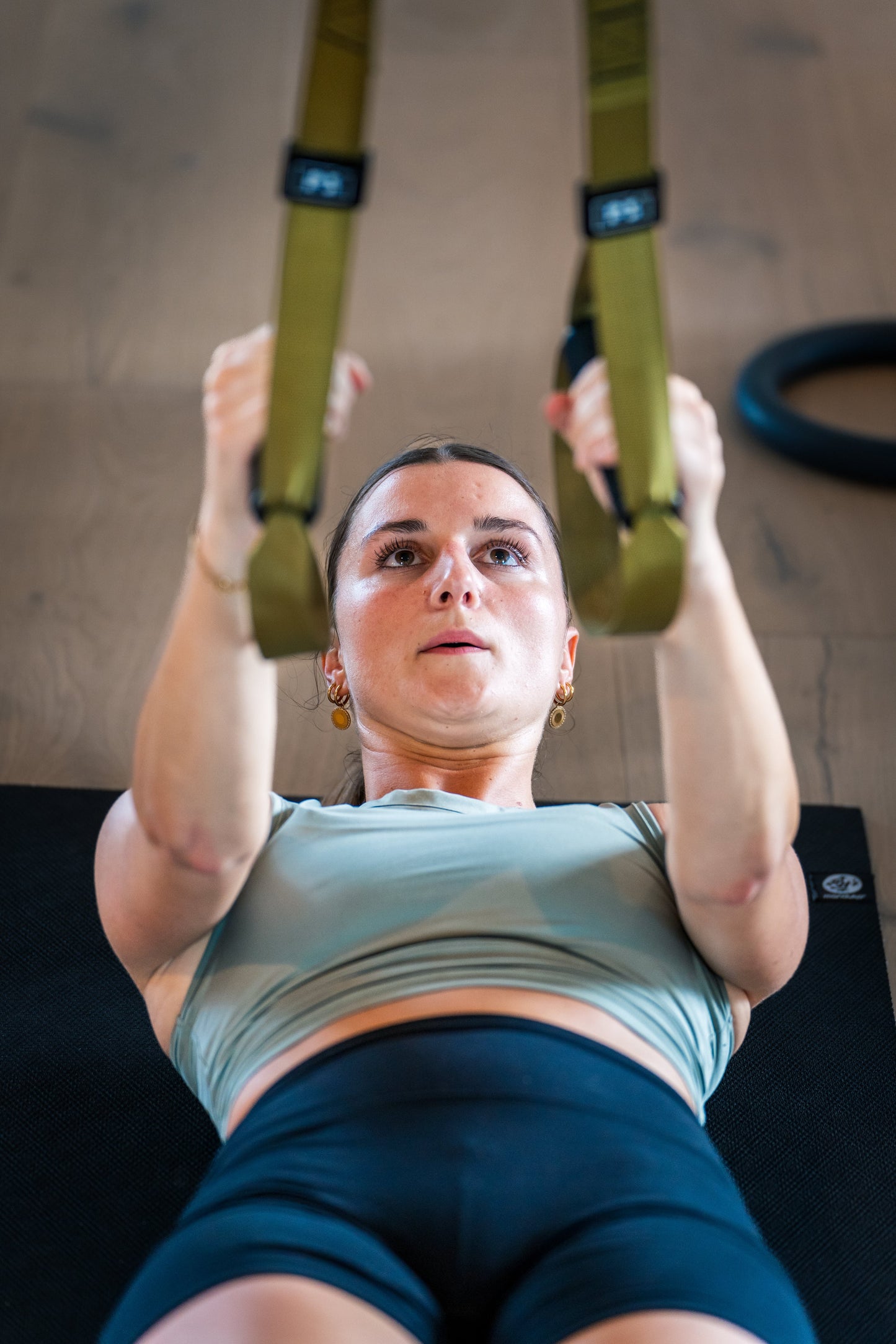 Eine Frau trainiert mit Turnringen auf einer Matte von Goldenbody Shop Ch.