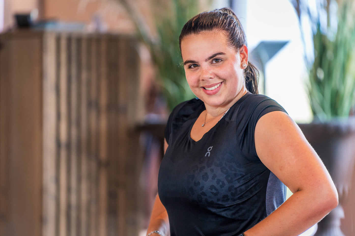 Eine lächelnde Frau in Sportkleidung posiert in einem Fitnessstudio von Goldenbody Shop Ch.