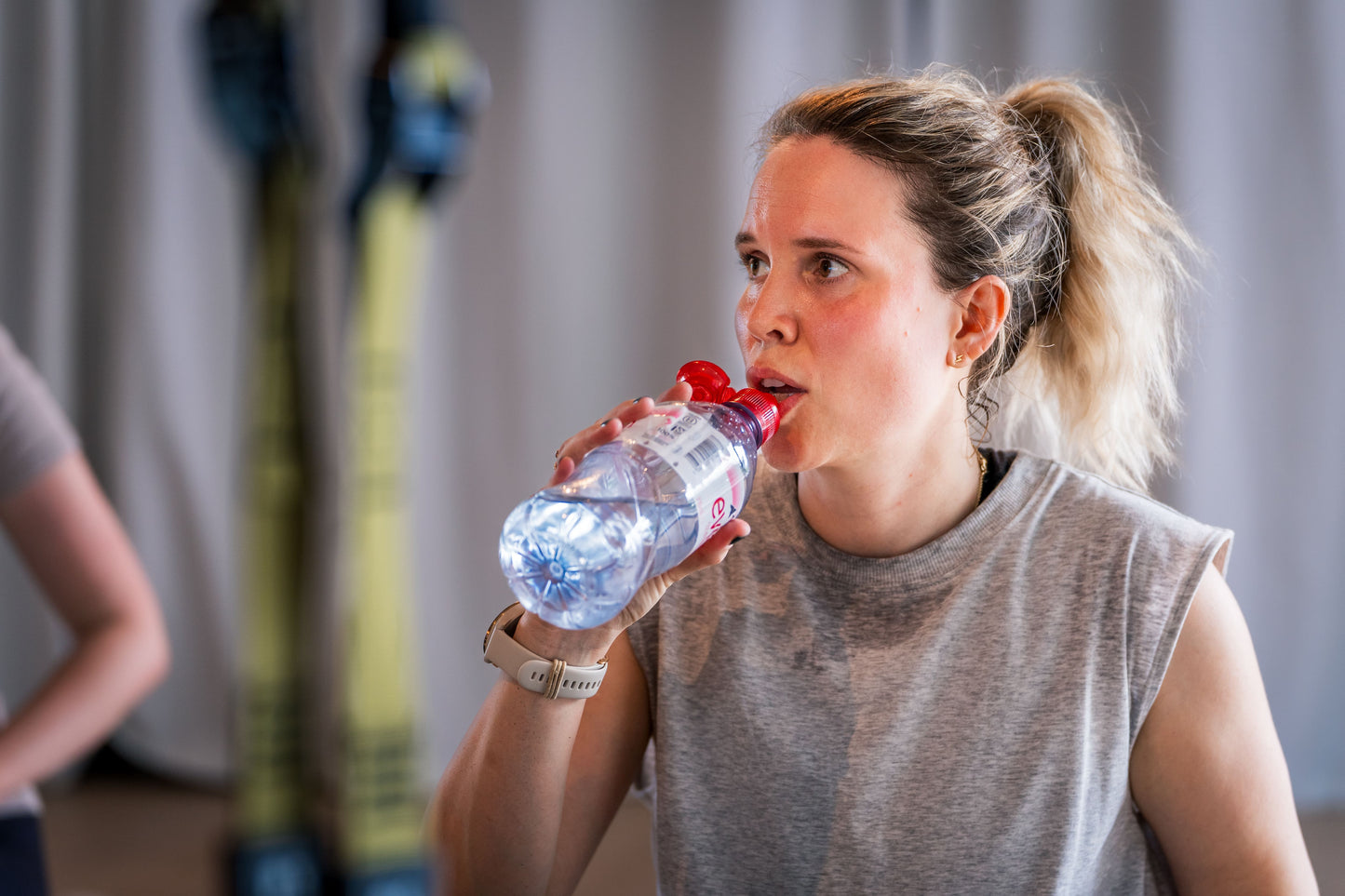 Eine Frau trinkt Wasser nach dem Training im Goldenbody Shop Ch Fitnessstudio.
