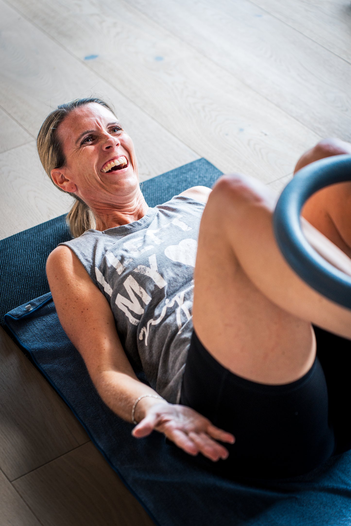Frau trainiert lachend mit Fitnessring auf Matte, Goldenbody Shop Ch fördert Fitness.