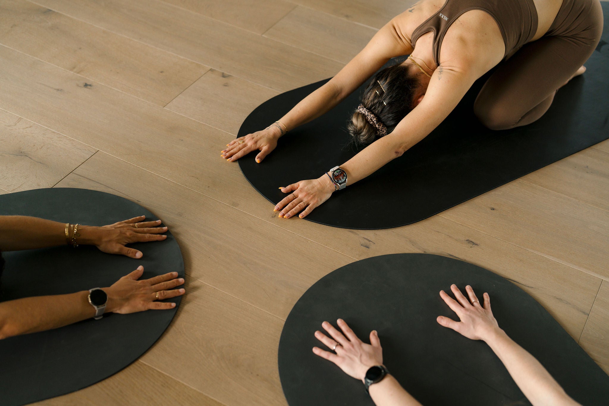 Personen praktizieren Yoga auf schwarzen Matten im Goldenbody Shop Ch Studio.