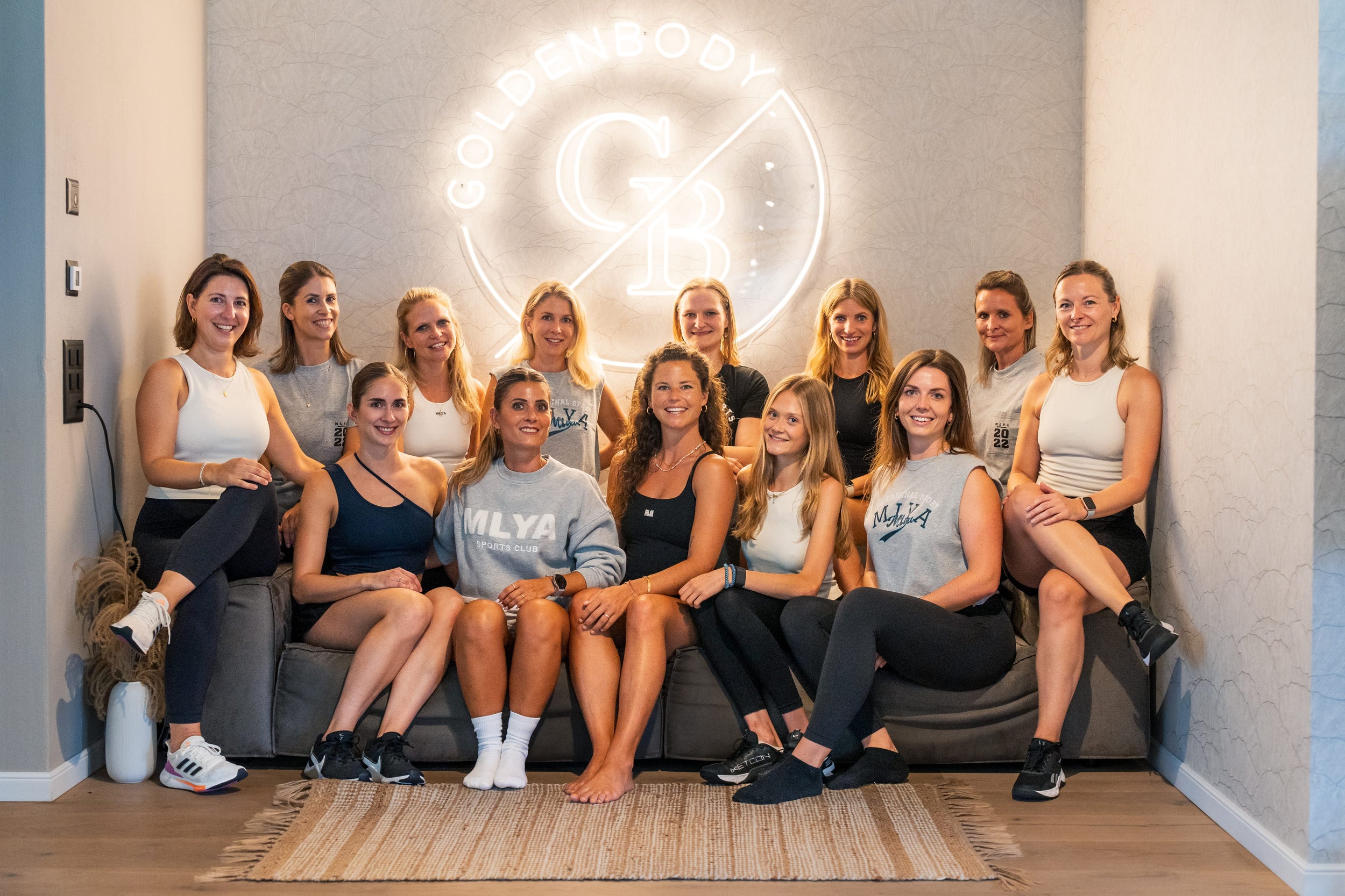 Eine Gruppe von Frauen posiert lächelnd vor dem Goldenbody Shop Ch Logo.