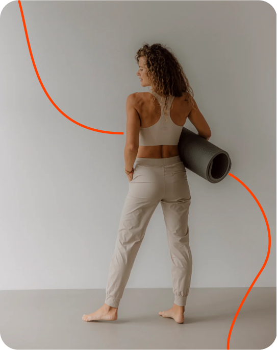 Frau mit Yogamatte von Goldenbody Shop Ch vor grauer Wand.
